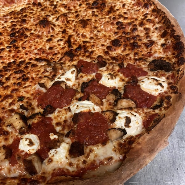 Close-up of a Kabylos Pizza with half plain cheese and half with red sauce, ricotta, and chicken.