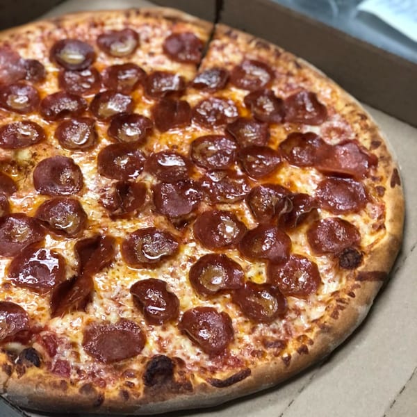 A close-up of a freshly baked Kabylos pepperoni pizza in a cardboard box, with one slice removed.
