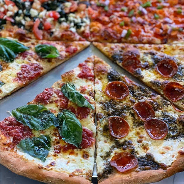 A close-up of various Kabylos Pizza slices, including Margherita and pepperoni with pesto.