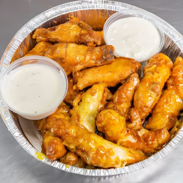 Kabylos Pizza's golden-brown chicken wings with two cups of dipping sauce in a foil container.